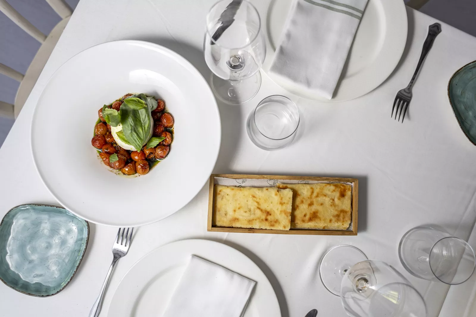 Mesa de restaurante en la que hay dos platos: uno con pan y otro con una ensalada